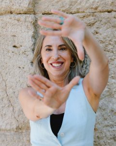 Mujer sonriente en sus 50 con canas visibles en llamada